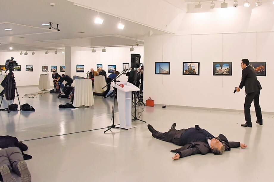 Mevlüt Mert Altintas (de pie, con su pistola) grita ante el público en una galería de Ankara tras asesinar al embajador ruso Andréi Karlov (en el suelo). / AFP