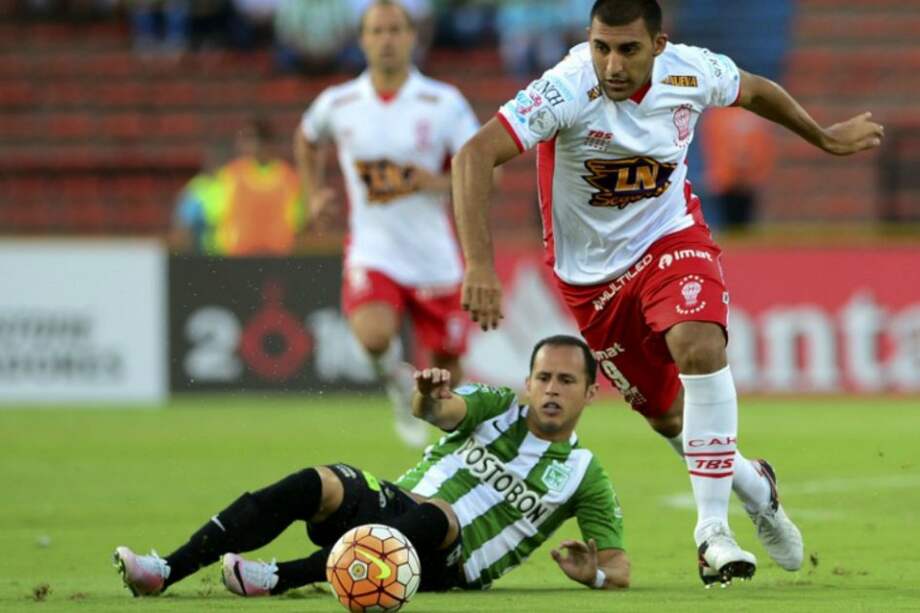 El venezolano de Nacional, Alejandro Guerra, disputa una pelota con Ramón Ábila de Huracán. / AFP