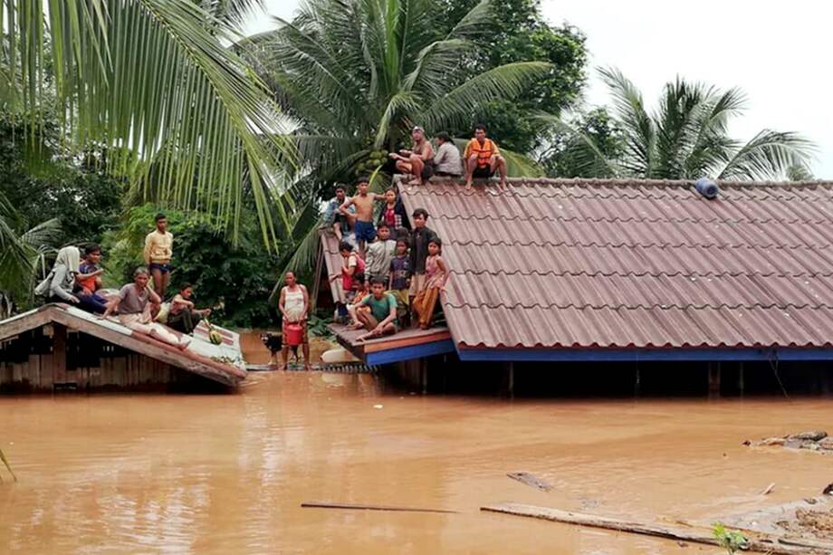 Un grupo de personas aguarda en lo alto de un tejado en una zona inundada tras el derrumbe de una presa hidroeléctrica en un pueblo cercano a la provincia de Attapeu, en Laos. / EFE