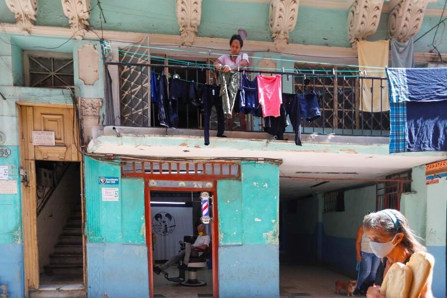 Una mujer protegida con tapabocas camina frente a una vivienda en La Habana (Cuba), en donde se registra una segunda ola de coronavirus.