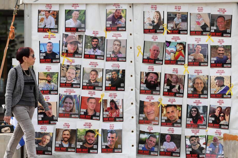Una mujer pasa junto a una exposición de carteles que piden la liberación de los rehenes israelíes, que fueron secuestrados por militantes durante los ataques del 7 de octubre de 2023 de Hamás, en el exterior del cuartel general militar de Kirya en Tel Aviv, Israel, el 17 de enero de 2025.