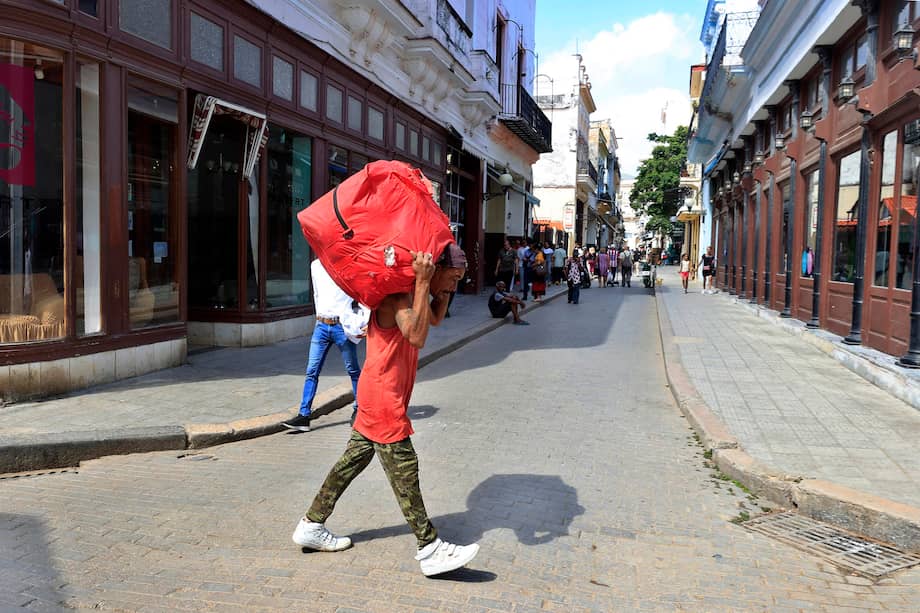 Una persona cargando una maleta por una calle, en La Habana (Cuba).
