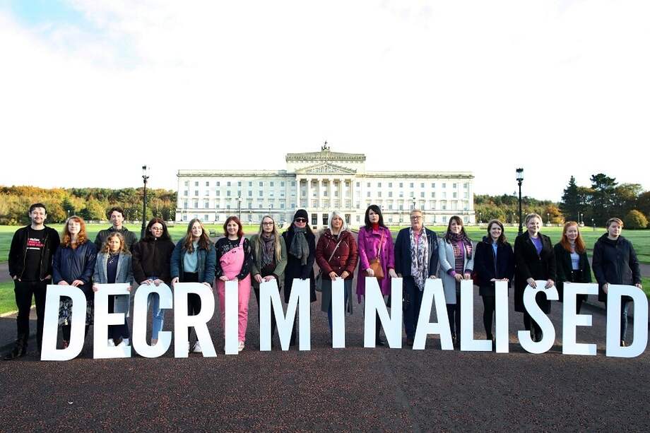 Los partidarios proabortistas posan con un cartel que dice "descriminalizado" al frente de los edificios del Parlamento en Belfast. / AFP