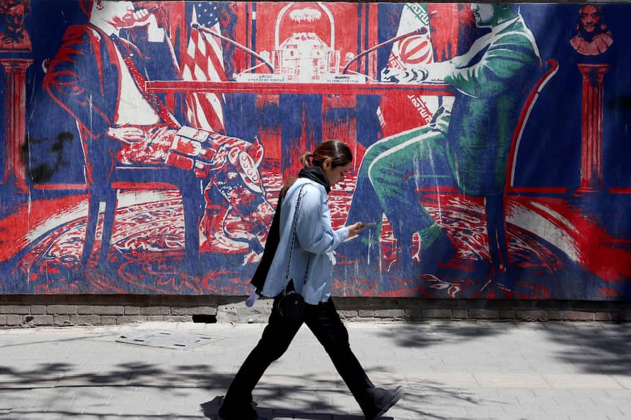 Una iraní camina junto a un mural que representa negociaciones entre Irán y Estados Unidos, en medio de un sentimiento en contra de Washington.