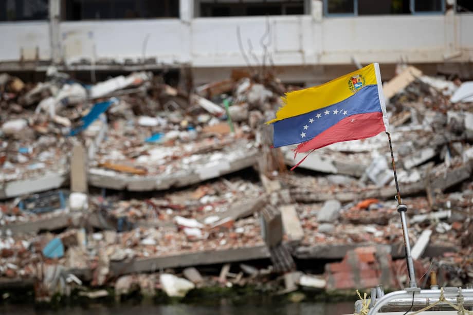 Una bandera de Venezuela frente a un edificio colapsado en La Guaira.