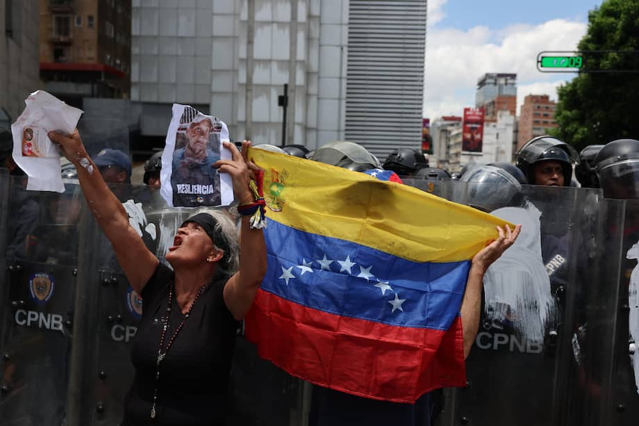 Una persona muestra carteles frente a integrantes del Cuerpo de Policía Nacional Bolivariana (CPNB).