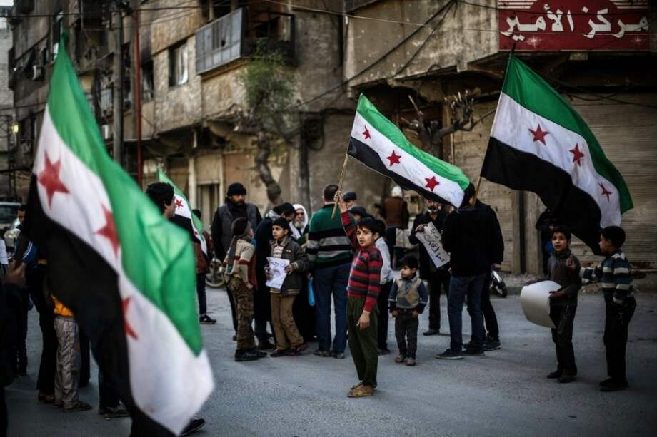 Un grupo de sirios ondea la bandera la bandera nacional en Duma (Siria) en protesta por los bombardeos contra la ciudad. / EFE