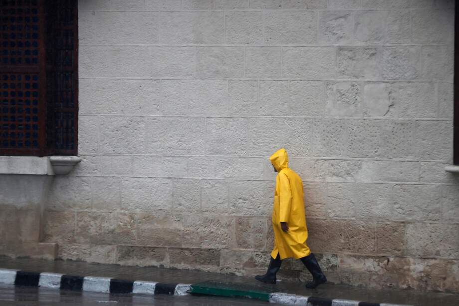 AME2831. SANTIAGO DE CUBA (CUBA), 28/10/2025.- Una persona se protege de la lluvia este martes, en Santiago de Cuba (Cuba). El Instituto de Meteorología (Insmet) de Cuba prevé que Melissa impacte en su extremo oriental como un huracán "extremadamente peligroso", probablemente como un categoría 4 (de 5) en la escala Saffir-Simpson. EFE/ Ernesto Mastrascusa