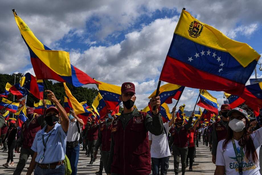 Un miembro de la Guardia Nacional Bolivariana y un grupo de civiles ondean banderas de Venezuela por la celebración del Día de la Independencia en Caracas.