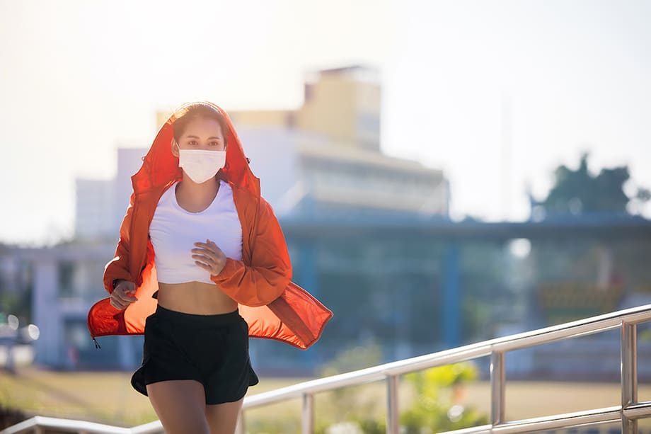 Mujer corriendo y usando una mascarilla de protección