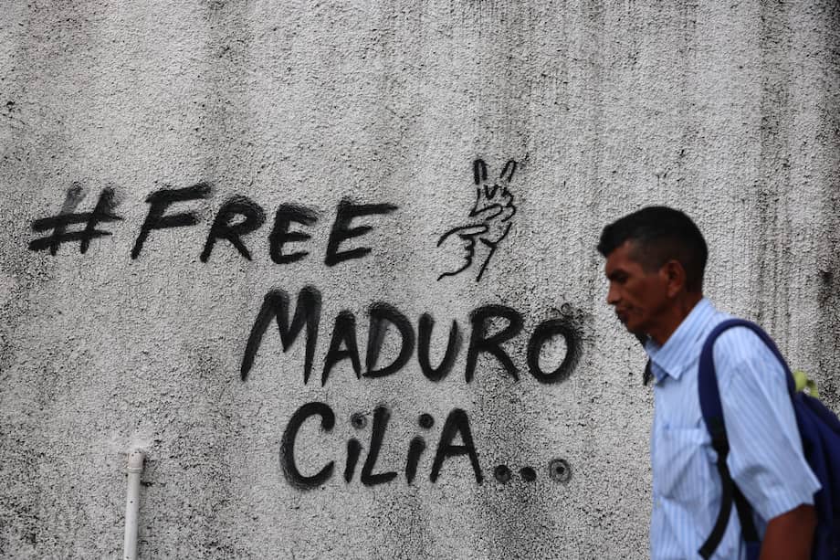 Un hombre camina frente a un mural en Caracas, Venezuela, con el cual se pide la liberación de Nicolás Maduro y Cilia Flores.
