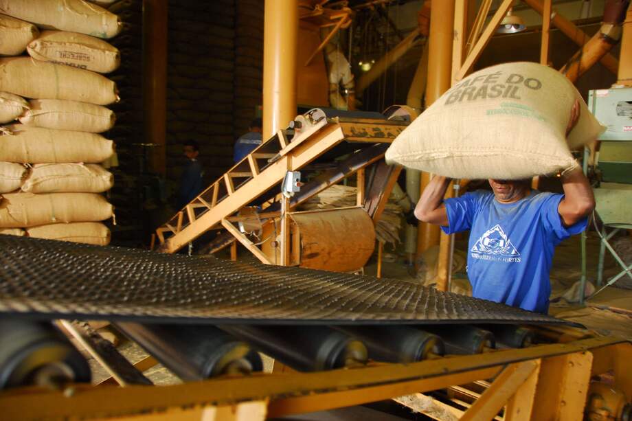 Un trabajador carga café en una cinta transportadora para ser enviado a Sumatra Cafes Brasil. / Bloomberg News.