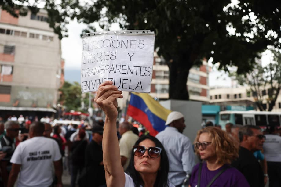 Una mujer sostiene un cartel durante una manifestación para pedir mejoras laborales este miércoles, mientras la primera ronda de negociación entre el Gobierno y la oposición de Venezuela, promovida por Estados Unidos, ocurre en el interior del hotel Meliá Caracas, en Caracas (Venezuela).