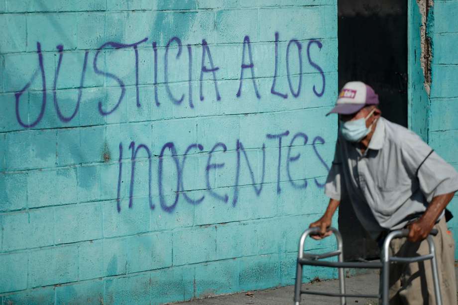 Un hombre camina frente a una pared pintada con la frase 'Justicia a los inocentes' en Reparto La Campanera, uno de los barrios que registraba mayor presencia de pandillas en Soyapango, El Salvador. 
