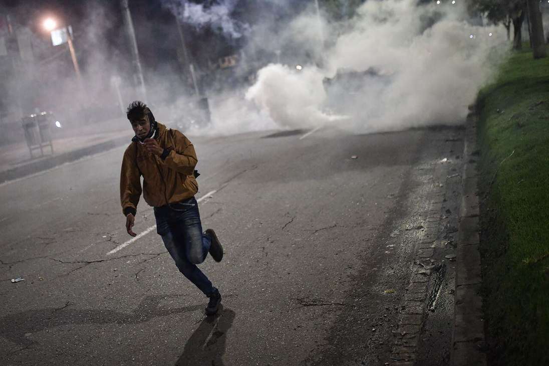 Un hombre corriendo del gas lacrimógeno.
