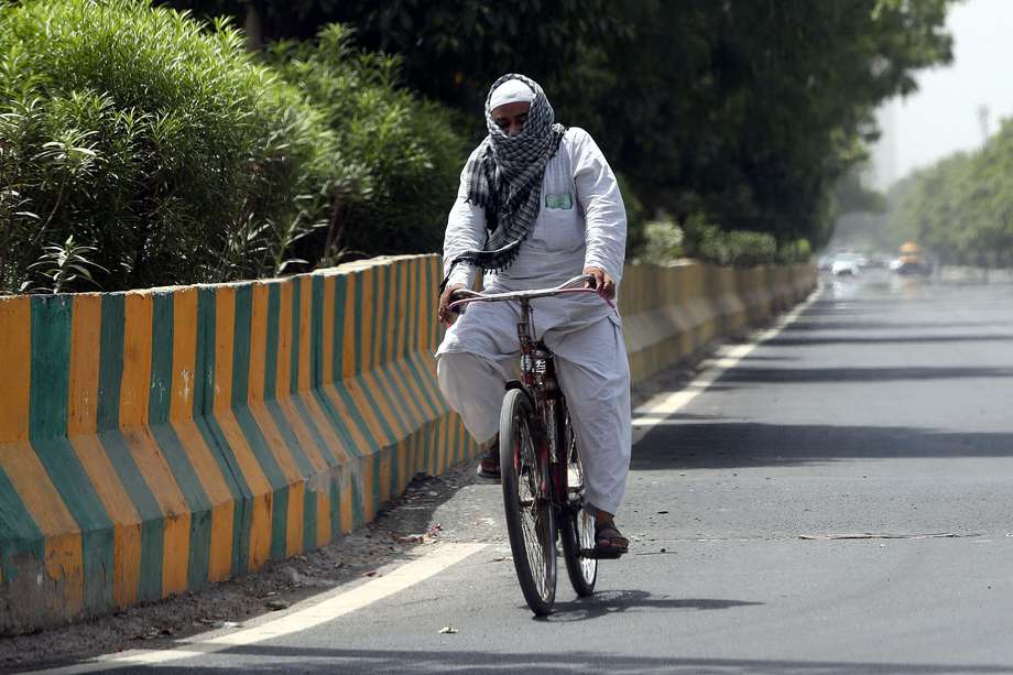 Un viajero recorre su bicicleta mientras se cubre la cabeza con una toalla en un día caluroso en Nueva Delhi, India, 29 de mayo de 2024. EFE/EPA/HARISH TYAGI
