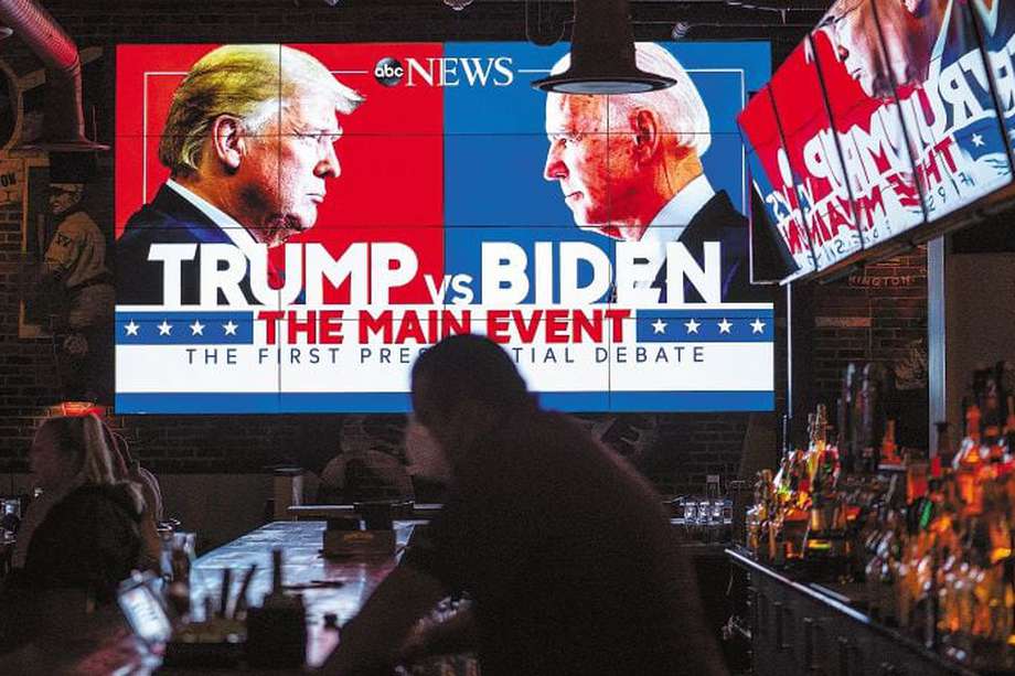 Una pantalla de televisión muestra los rostros de Donald Trump y Joe Biden enfrentados. 
