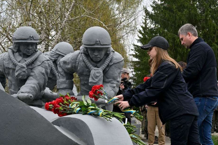 Un grupo de personas deja flores en el monumento que rinde homenaje a los bomberos que murieron durante el desastre de Chernóbil.