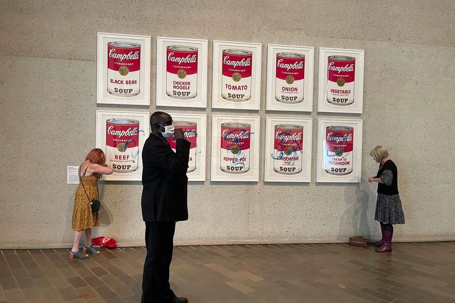 Dos activistas ambientales se adhirieren este miércoles con pegamento a las  "Latas de sopa Campbell" del artista estadounidense Andy Warhol en la Galería Nacional de Camberra. EFE/ Stop Fossil Fuel Subsidies 
