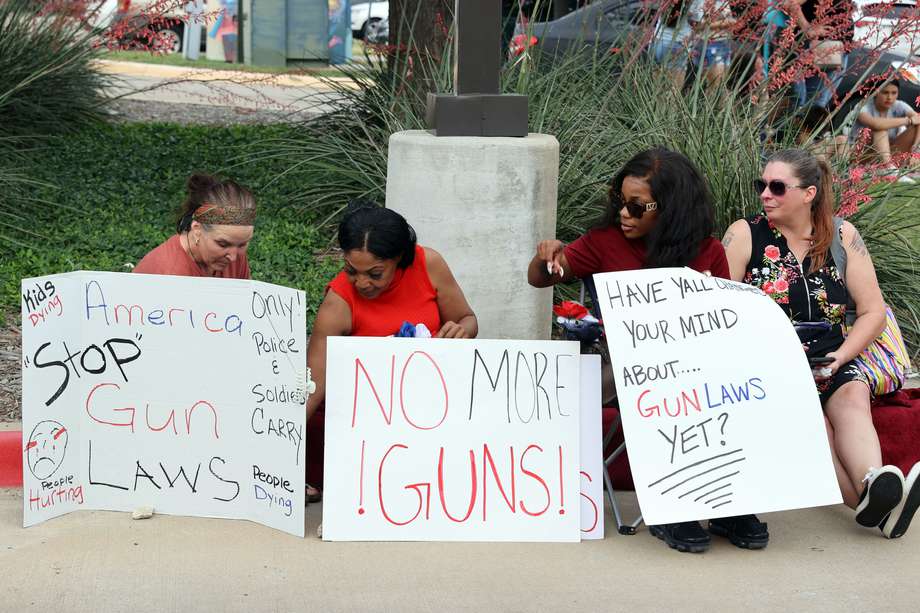 Las mujeres sostienen carteles sobre las armas durante una vigilia en recuerdo de las personas que murieron durante el tiroteo masivo en el Allen Premium Outlets Mall, frente al Allen Premium Outlets en Allen, Texas, EE. UU., 07 de mayo de 2023. Nueve personas, incluido el pistolero fueron asesinados el 06 de mayo de 2023.
