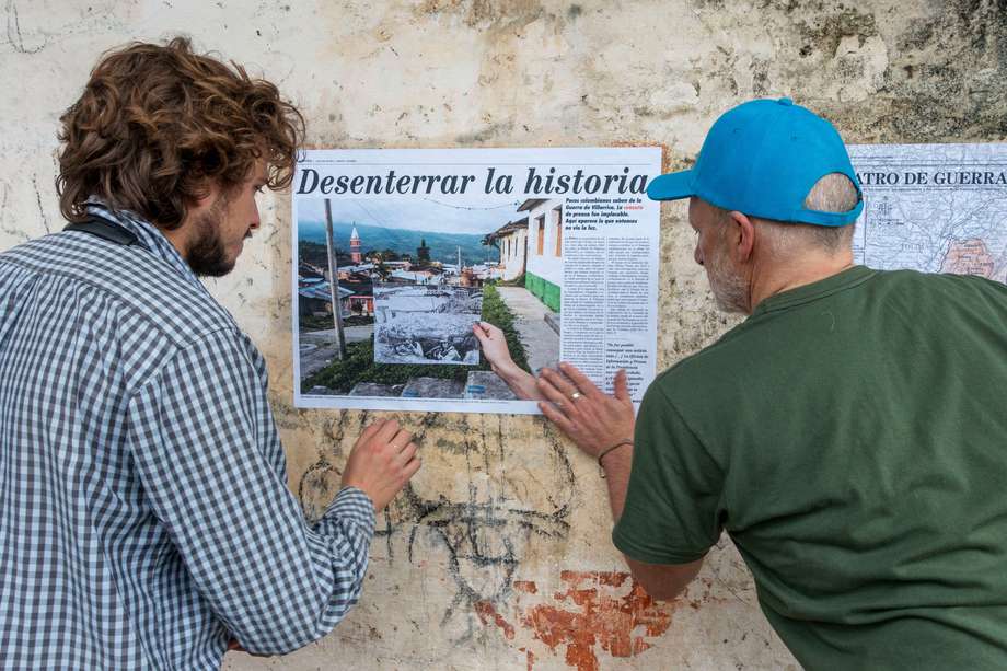 Stephen Ferry (derecha) Y Tomás Mantilla, coautor, pegan la primera página del informe La Época en una de las paredes de la escuela vocacional de La Colonia, abandonada tras la guerra.