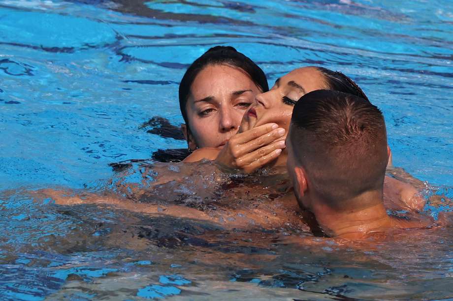 Miembros de su equipo sacan del agua a la nadadora Anita Álvarez. (Photo by Peter Kohalmi / AFP)
