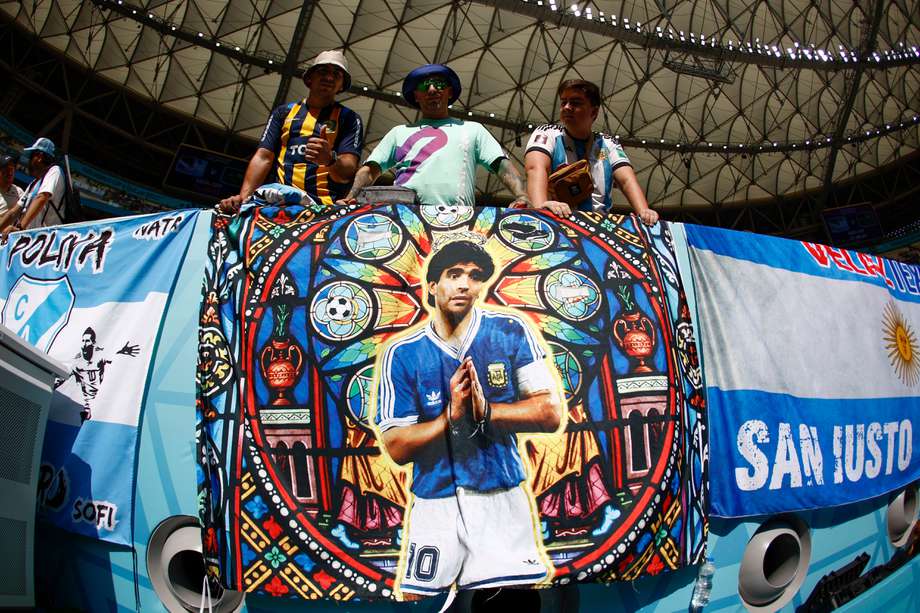 Hinchas de Argentina posan con una bandera con la imagen de Diego Armando Maradona en Catar.
