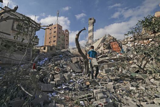 Un joven palestino busca artículos rescatables en medio de los escombros del edificio Kuhail que fue destruido en un ataque aéreo israelí en la mañana en la ciudad de Gaza el 18 de mayo. El edificio tenía una imprenta, accesorios universitarios y una instalación de almacenamiento de libros para institutos educativos en Gaza.