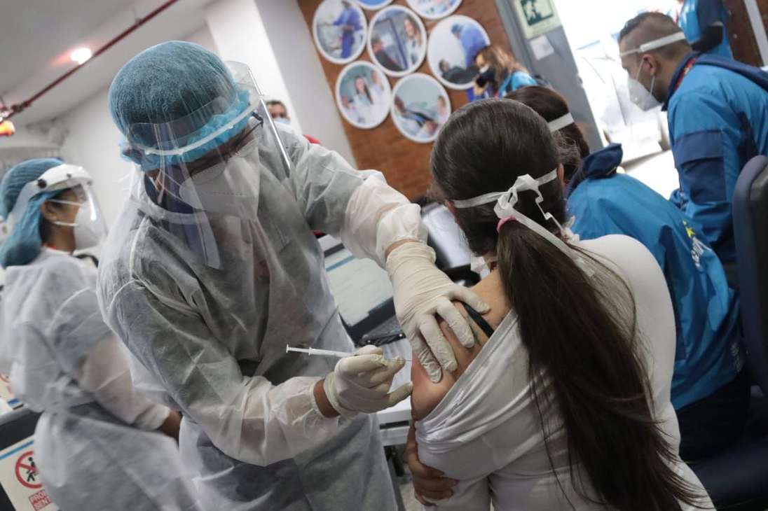 Un hombre aplicando la vacuna a una mujer