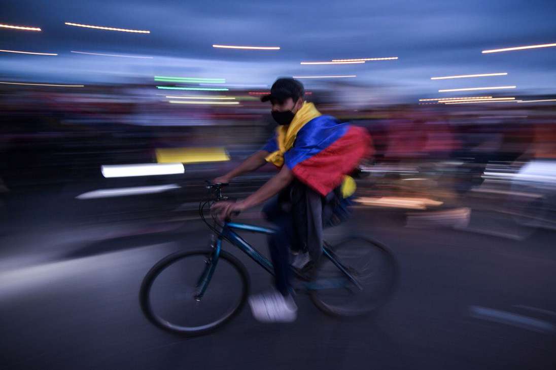 Un hombre en bicicleta con la bandera de Colombia en los hombros