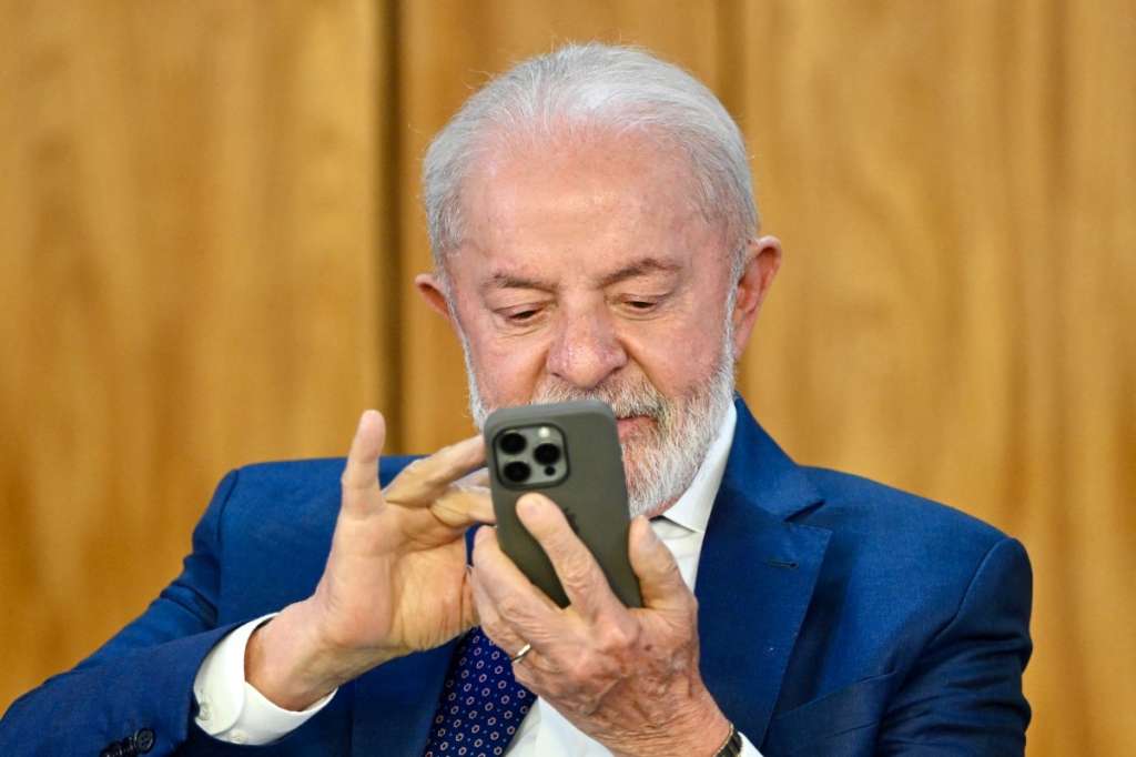 (FILES) Brazil's President Luiz Inacio Lula da Silva watches his phone during the signing of a decree with measures to mitigate the economic impact of the US government's increase of up to 50% in import tariffs on Brazilian products at the Planalto Palace in Brasília on August 13, 2025.