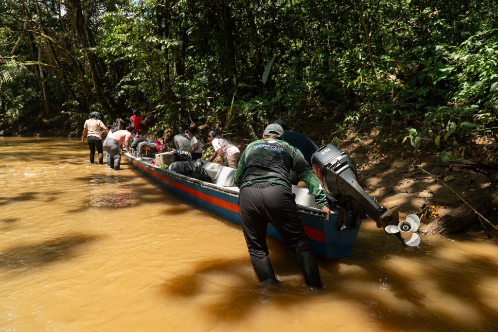 Ante los bajos niveles de la quebrada Jácome, imprevistos para mediados de año, integrantes del resguardo indígena coreguaje de Jácome, en la Amazonia colombiana, empujan la lancha para avanzar en su recorrido.