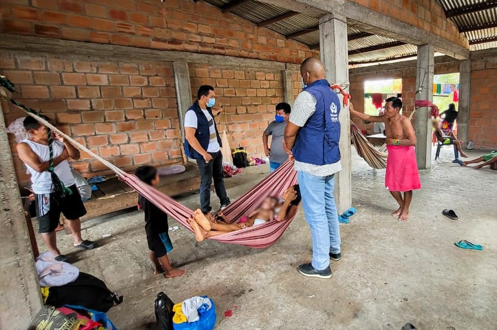 Un grupo de personas en un lugar de Arauca, con dos funcionarios de la Defensoría del Pueblo que visten chalecos azules.