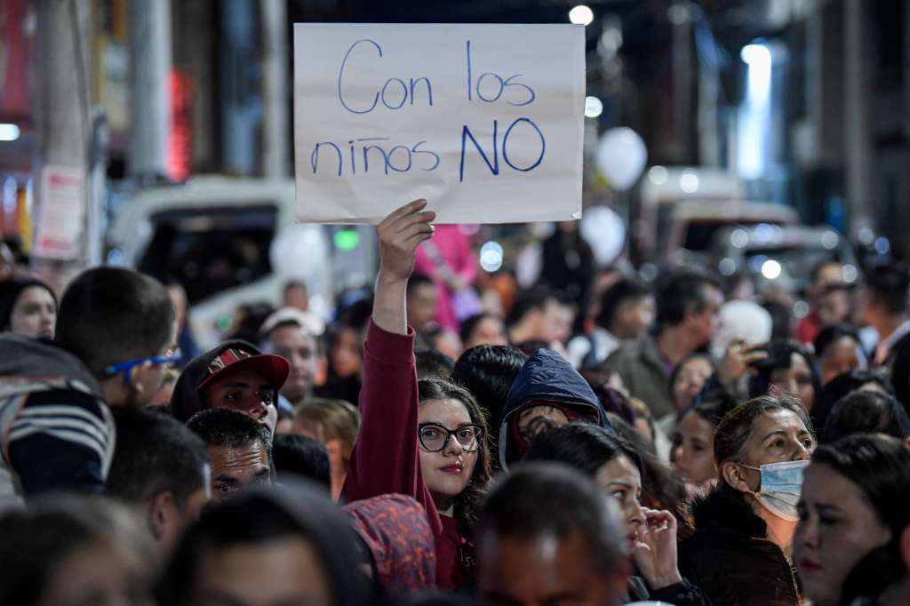 Asistente a la velatón sostiene un cartel para rechazar la violencia infantil.