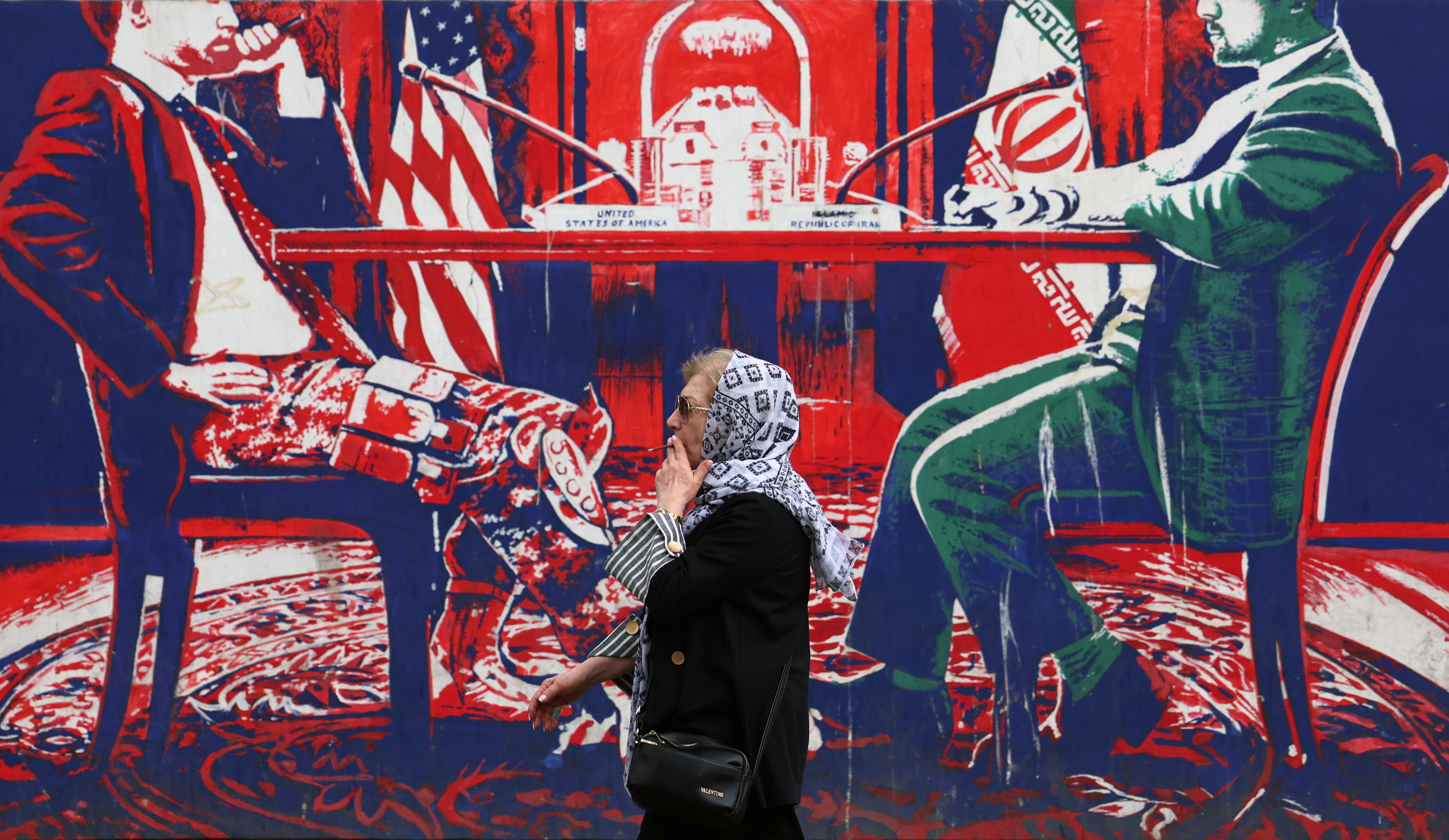 TEHRAN (Iran (Islamic Republic Of)), 07/04/2025.- An Iranian woman smokes as she walks next to an anti-US mural, next to the former US Embassy in Tehran, Iran, 07 April 2025. Amid ongoing tensions between Iran and the USA, according to the Iranian Foreign Ministry, Iranian foreign minister Abbas Araghchi said on 06 April 2025 that no negotiations have been held between Iran and the USA yet, as we have stated our position and are open for diplomacy and negotiations, but indirectly. (Teherán) EFE/EPA/ABEDIN TAHERKENAREH