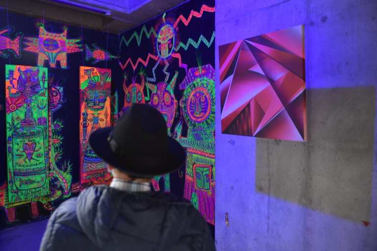 Un hombre viendo una pared pintada con colores de neón
