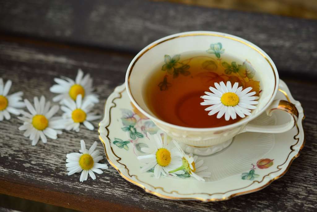 Imagen de una flor de manzanilla flotando encima de una taza de té.
