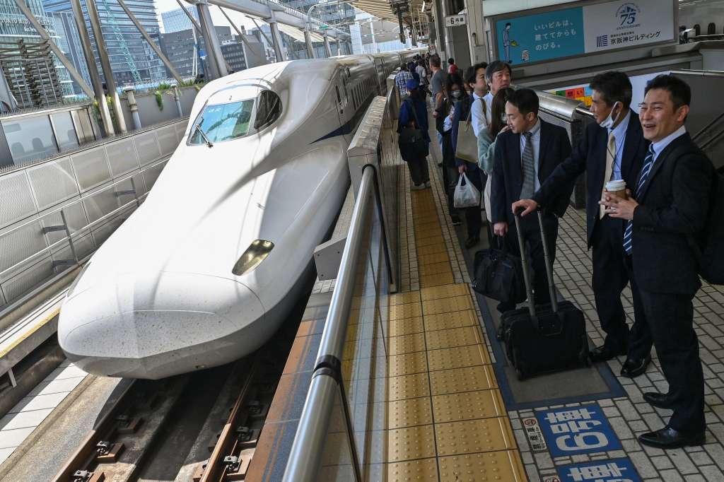 Passengers wait on the platform as a Kodama bullet train, or "shinkansen" service to the city of Nagoya arrives to pick up passengers at Tokyo station in central Tokyo on April 17, 2024.