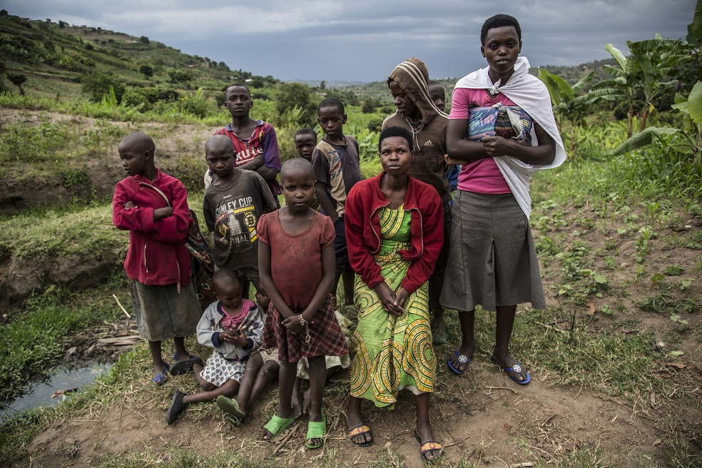 Villagers pose for a photo near a well-spring that sits in the valley that separates two villages on adjascent hills, at the border between Musambira and Nyarubaka sectors of Kamonyi District, on March 4, 2019. - Two villages on adjascent hills are re-learning to share all they have, including a well-spring at the bottom of the valley, after 1994 genocide. More than a thousand residents of the town were massacred in the days following the outbreak of inter-ethnic violence, a genocide in which over 800,000 mostly Tutsi people were slaughtered between April to July 1994, according to the UN. (Photo by JACQUES NKINZINGABO / AFP)