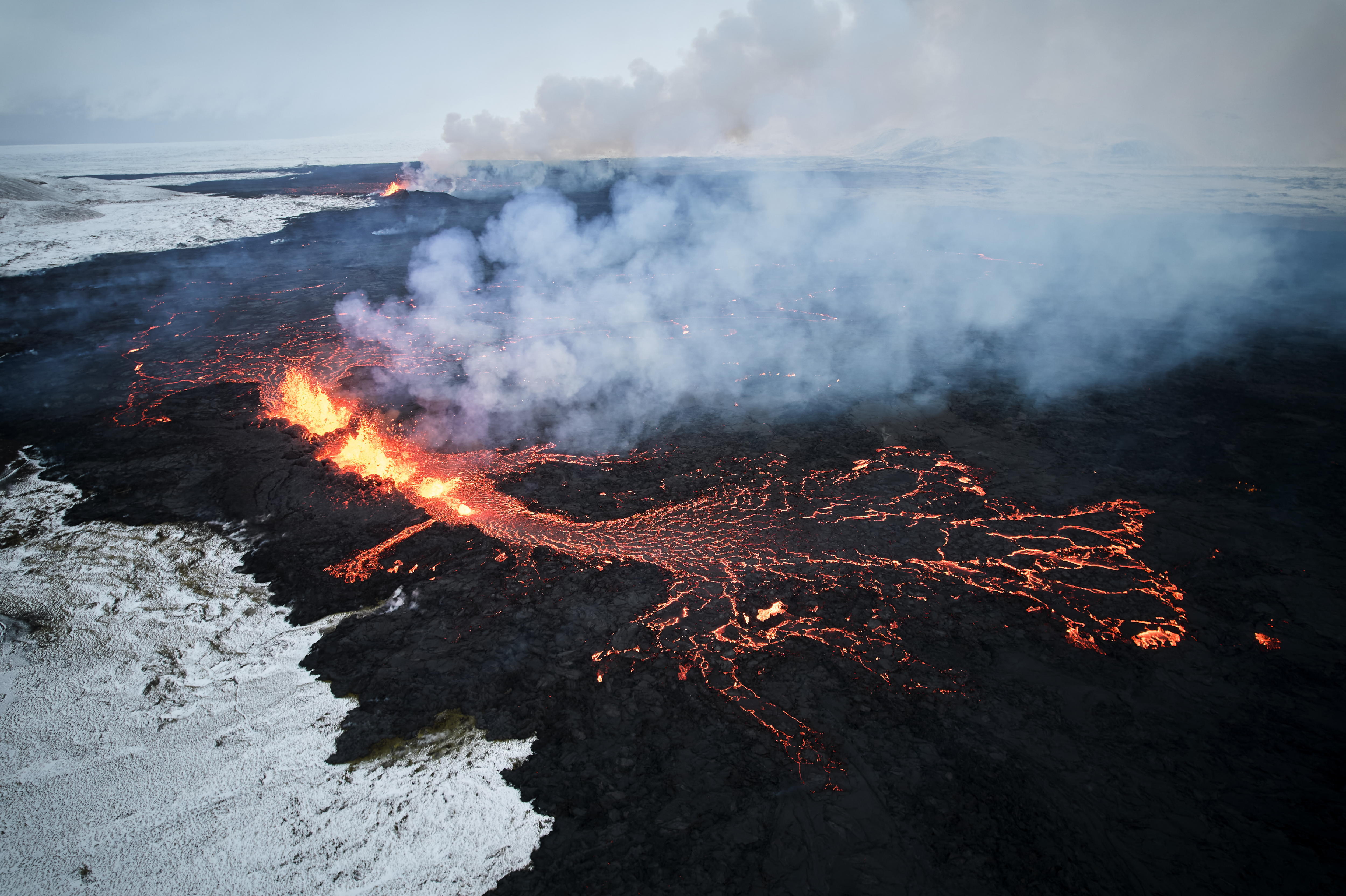 -FOTODELDÍA- EA2876. GRINDAVIK (ISLANDIA), 19/12/2023.- Fotografía aérea tomada con un drone muestra lava y humo saliendo de una fisura volcánica durante una erupción cerca de la ciudad de Grindavik, en la península de Reykjanes (Islandia). La Oficina Meteorológica de Islandia (OMI) anunció el inicio de una erupción volcánica fisural cerca del cráter de Sundhnuka, al noreste de Grindavik, en la noche del 18 de diciembre, tras semanas de intensa actividad sísmica en la zona. La potencia y la actividad sísmica de la erupción han disminuido con el tiempo, informó la OMI el 19 de diciembre, añadiendo que se han registrado unos 320 seísmos desde el inicio de la erupción. EFE/EPA/ANTON BRINK