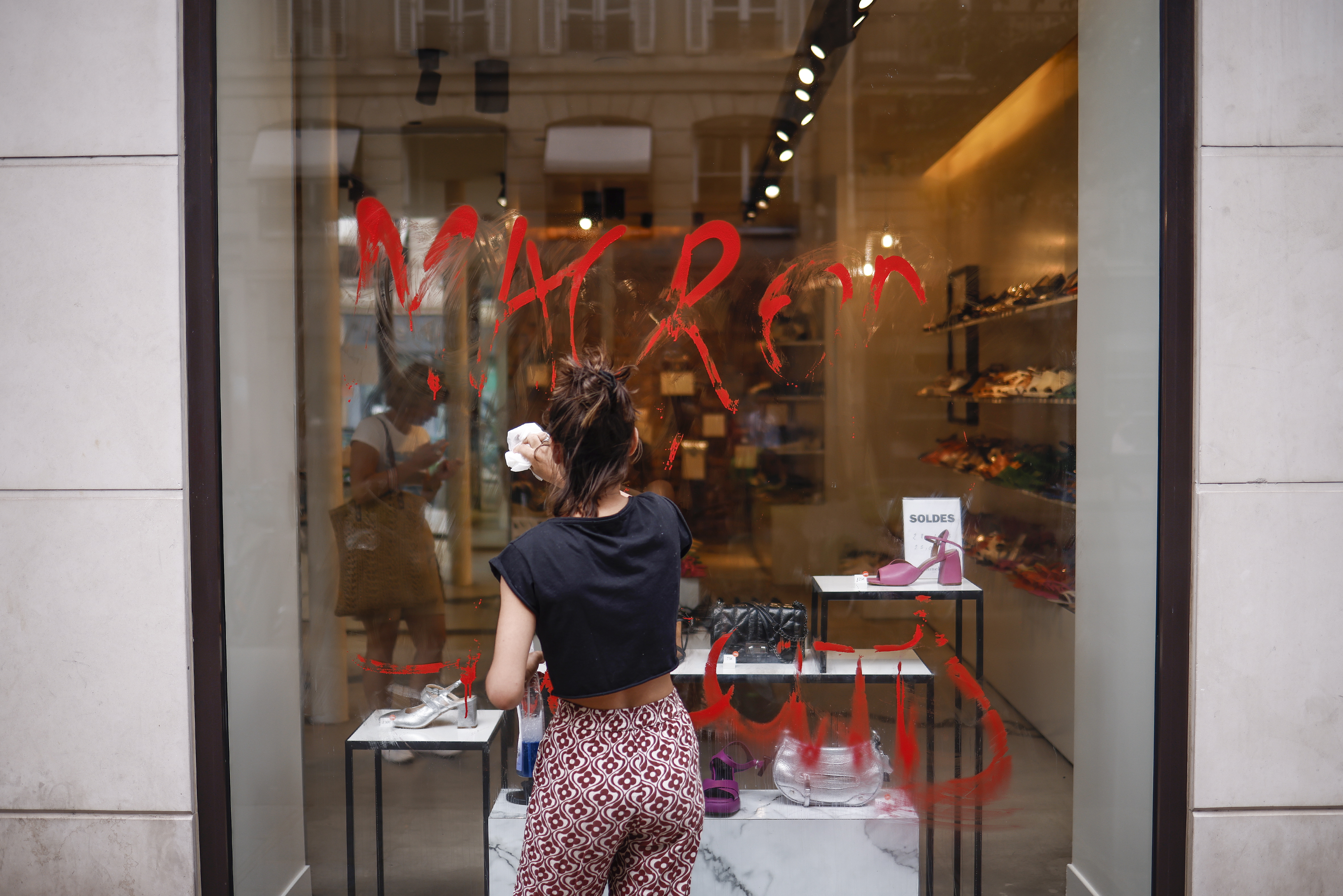 Paris (France), 30/06/2023.- A storekeeper cleans a Macron graffiti written on the storefront in Paris, France, 30 June 2023. Violence broke out all over France after police fatally shot Nael, a 17-year-old, during a traffic stop in Nanterre on 27 June. (Disturbios, Francia) EFE/EPA/YOAN VALAT