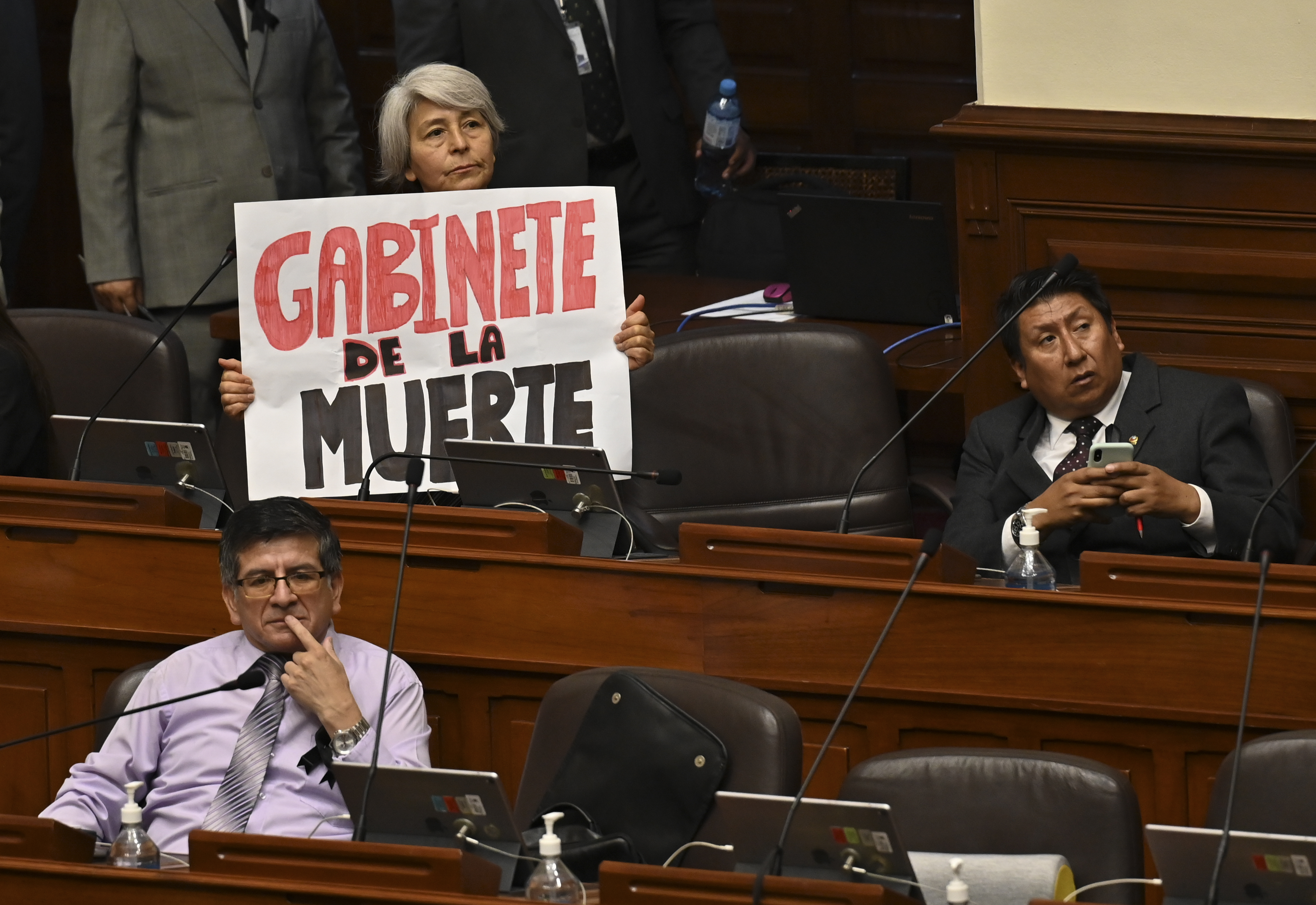 AME5315. LIMA (PERÚ), 10/01/2023.- Una mujer miembro del Congreso sostiene una pancarta mientras escuha al primer ministro de Perú, Alberto Otarola, mientras él y su gabinete enfrentan un voto de confianza, hoy, en Lima (Perú). El primer ministro de Perú, Alberto Otárola, quien encabeza el segundo gabinete del Gobierno de Dina Boluarte, llegó este martes al Congreso para pedir el voto de confianza del Parlamento, un proceso obligatorio que deben pasar tras el nombramiento, en medio de la escalada de violencia en el sur del país por protestas antigubernamentales que el lunes dejaron un saldo de 17 fallecidos. EFE/ Cris Bouroncle / Pool