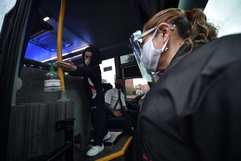Un niño aplicándose gel antibacterial al subirse a la ruta.