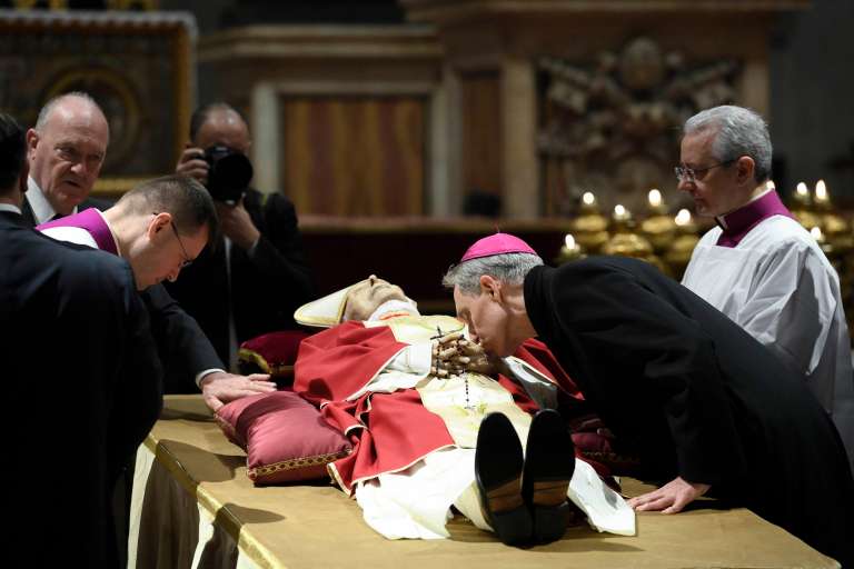 Vatican City (Vatican City State (holy See)), 02/01/2023.- A handout photo made available by Vatican Media shows Archbishop Georg Gaenswein kissing the hand of late Pope Emeritus Benedict XVI (Joseph Ratzinger) as his body lies in state in Saint Peter's Basilica for public viewing, Vatican City, 02 January 2023. Former Pope Benedict XVI died on 31 December at his Vatican residence, aged 95. For three days, starting from 02 January, the body will lay in state in St Peter's Basilica until the funeral on 05 January. (Papa) EFE/EPA/VATICAN MEDIA HANDOUT EDITORIAL USE ONLY/NO SALES