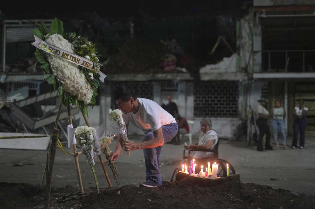 AME3260. CALI (COLOMBIA), 24/08/2025.- Una persona pone una ofrenda de flores en una 'velatón' por la paz y la memoria este domingo, frente a la Base Aérea Marco Fidel Suárez, en Cali (Colombia). Centenares de personas, vestidas de blanco y con velas en mano, se reunieron en el lugar del atentado que el jueves sacudió a la ciudad colombiana en memoria de los seis civiles que murieron en la explosión de un camión bomba. EFE/ Ernesto Guzmán