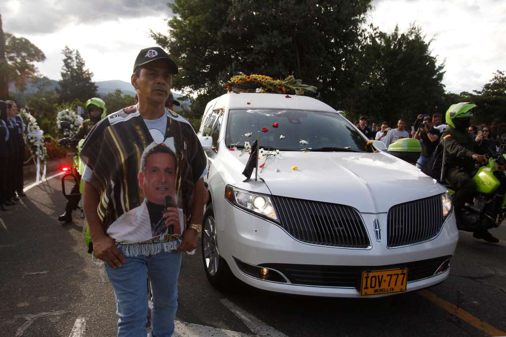 AME6426. MEDELLÍN (COLOMBIA), 30/07/2022.- Seguidores del cantante colombiano Darío Gómez acompañan la caravana con el cortejo fúnebre que lleva el cuerpo del artista rumbo a su entierro en el cementerio Campos de Paz, hoy, en Medellín (Colombia). Cientos de fanáticos se volcaron a las calles de Medellín para acompañar por última vez al cortejo fúnebre que traslada el cuerpo del cantante Darío Gómez rumbo a la iglesia Santa Gema, donde se realizarán las exequias de manera privada por disposición de la familia y luego de varios días espontáneos homenajes de fanáticos y la ciudadanía en general. La muerte del compositor y cantante colombiano de música popular Darío Gómez, de 71 años de edad, ha provocado una oleada de reacciones de toda la sociedad en Colombia, donde es considerado un ícono y el máximo exponente del género popular. EFE/ Luis Eduardo Noriega