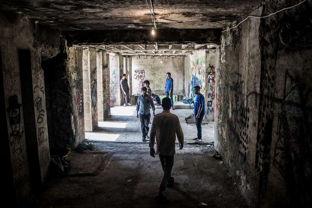 Biha?, Bosnia. Migrantes y refugiados caminan por un pasillo en el dormitorio abandonado donde muchos se han congregado como punto de escala en su viaje hacia Europa. / Kamila Stepien/MSF