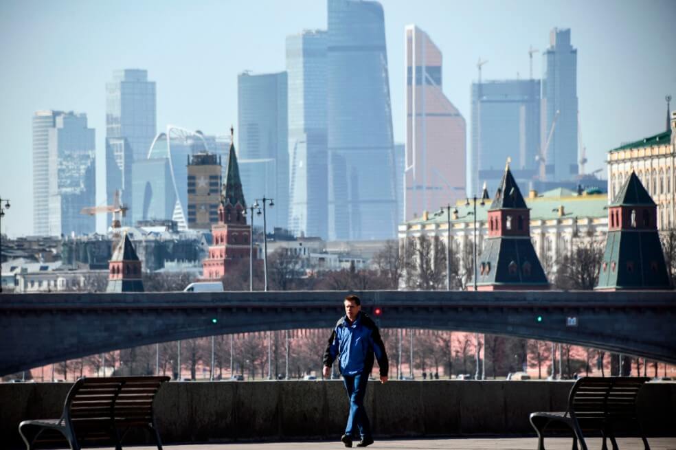 Un hombre camina sobre una orilla del río Moskva, con el Kremlin y los edificios del Centro Internacional de Negocios de Moscú (Ciudad de Moskva) vistos de fondo, en el centro de Moscú el 25 de marzo de 2020. / AFP