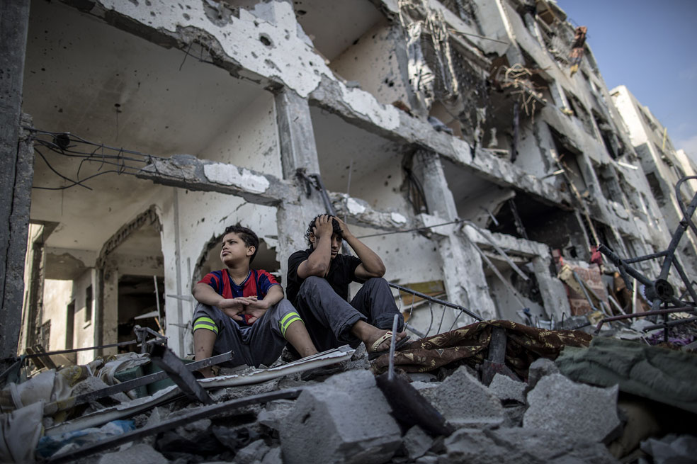 Dos hermanos frente a lo que quedó de su casa después de ataques perpetrados por Israel en el marco de su ofensiva Margen Protector en la Franja de Gaza. / AFP