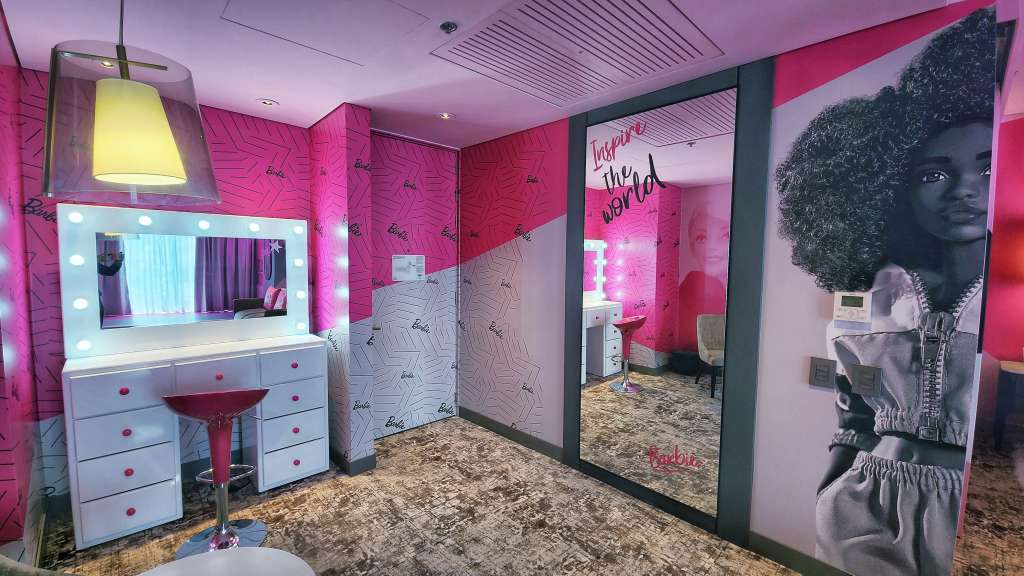 Los tonos rosados adornan la pared junto a imágenes estampadas de Barbie y sus amigos y obras de arte contemporáneas de la icónica muñeca.